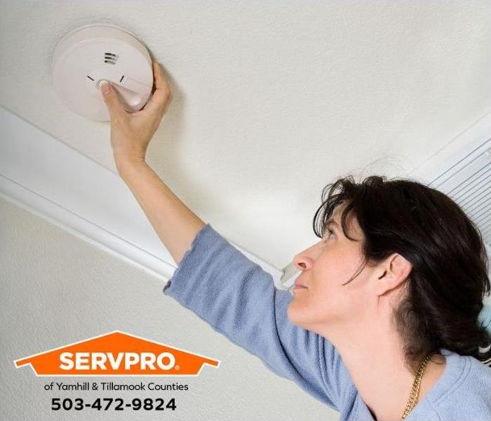 A person is inspecting a smoke detector.