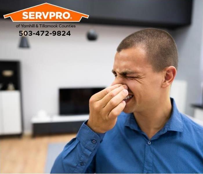 A person holds their nose against a bad odor in a room.